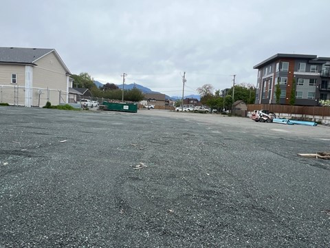 A parking lot with a few cars and buildings in the background.