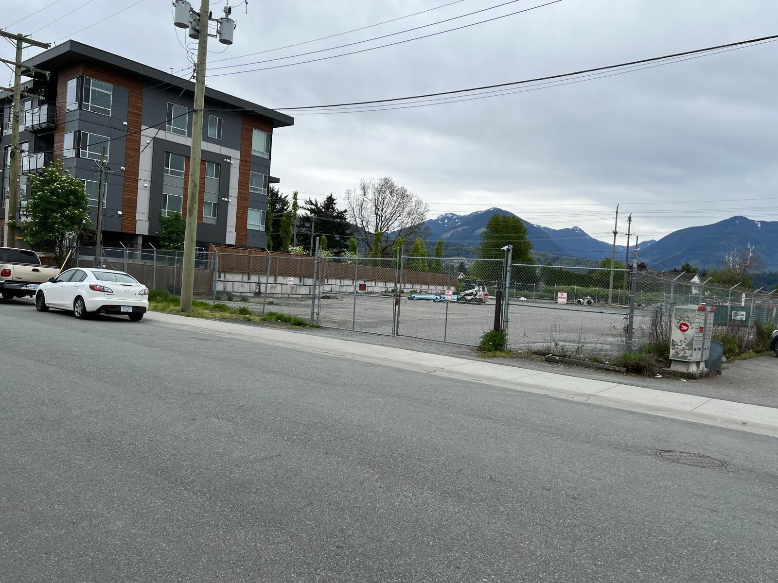 A white car is parked on the side of a road in front of a building.