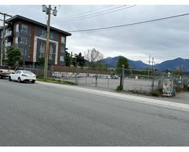 A white car is parked on the side of a road in front of a building.