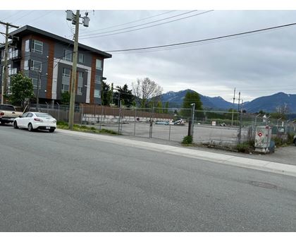A white car is parked on the side of a road in front of a building.