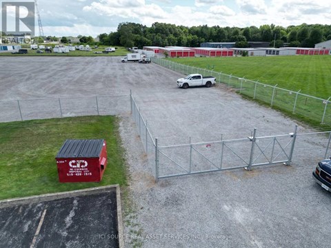 A red container with the letters "CP" on it is in the foreground of a gravel lot.