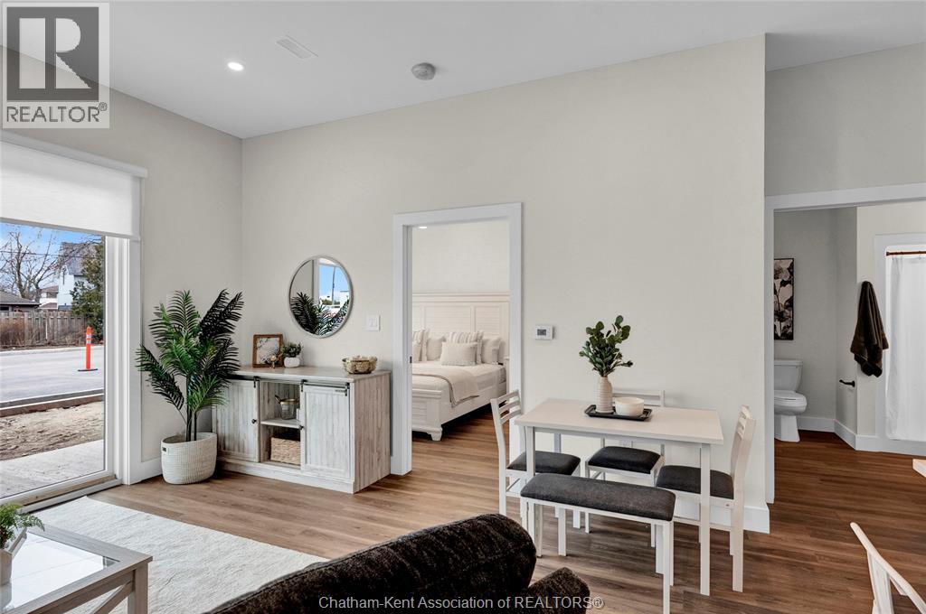 A well-lit, modern bedroom with a large bed and a small table with a plant on it.