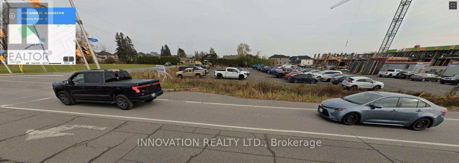 A black pickup truck is driving on a road with a sign that says "INNOVATION REALTY LTD., Brokerage".