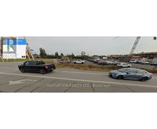 A black pickup truck is driving on a road with a sign that says "INNOVATION REALTY LTD., Brokerage".