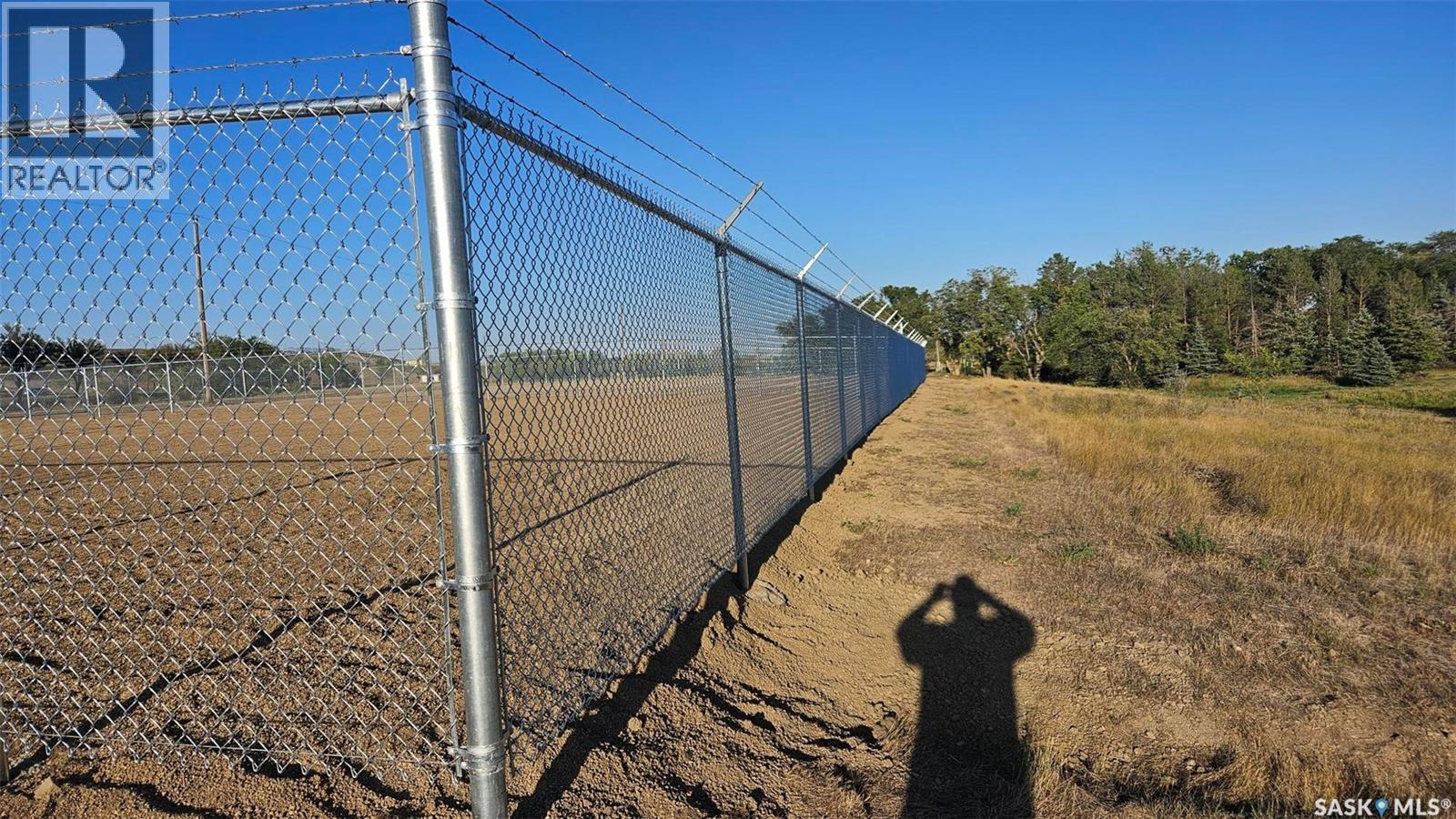 A person is standing in front of a chain link fence with a sign that says REALTOR.