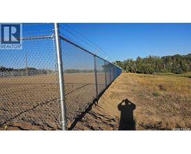 A person is standing in front of a chain link fence with a sign that says REALTOR.