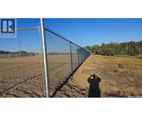 A person is standing in front of a chain link fence with a sign that says REALTOR.
