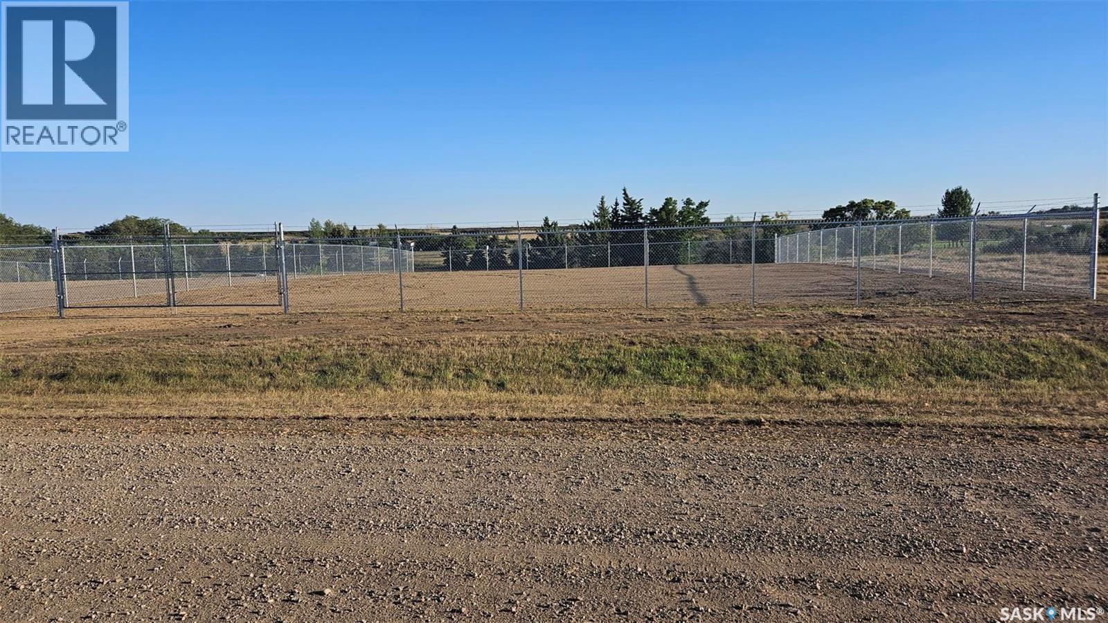 A large, empty field with a fence and trees in the distance.