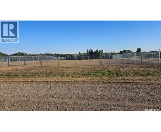 A large, empty field with a fence and trees in the distance.