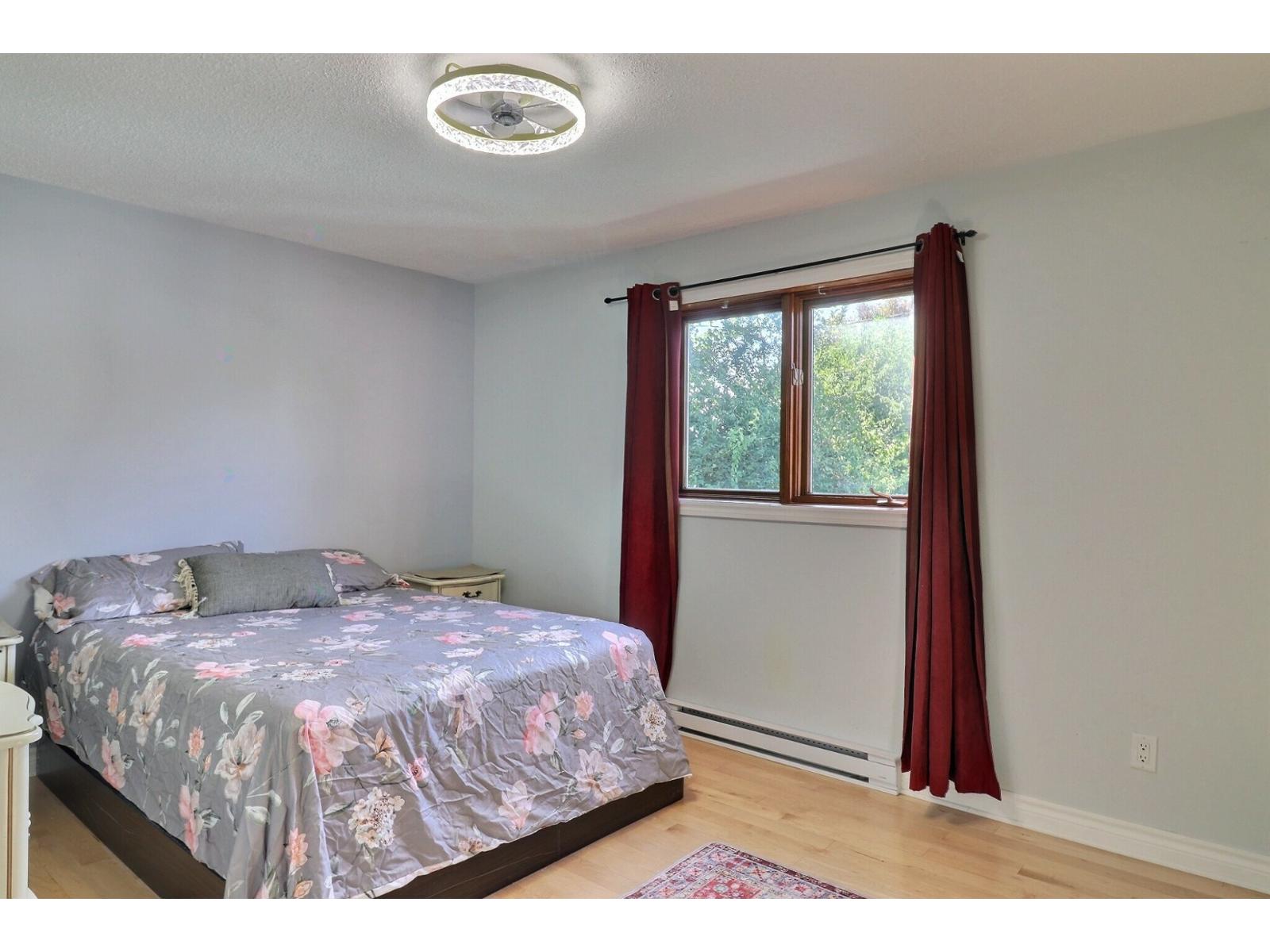 A bedroom with a floral bedspread and red curtains.