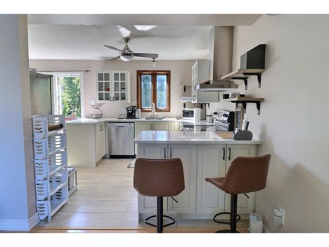 A kitchen with a white counter and brown chairs.
