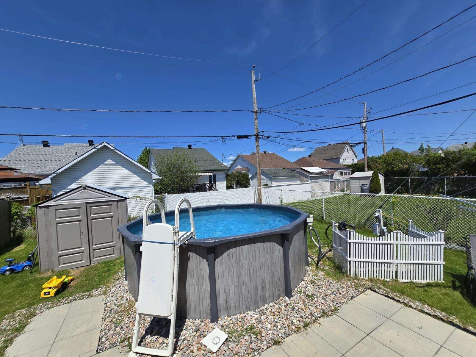 A small residential backyard with a pool and a fence.