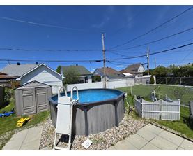 A small residential backyard with a pool and a fence.