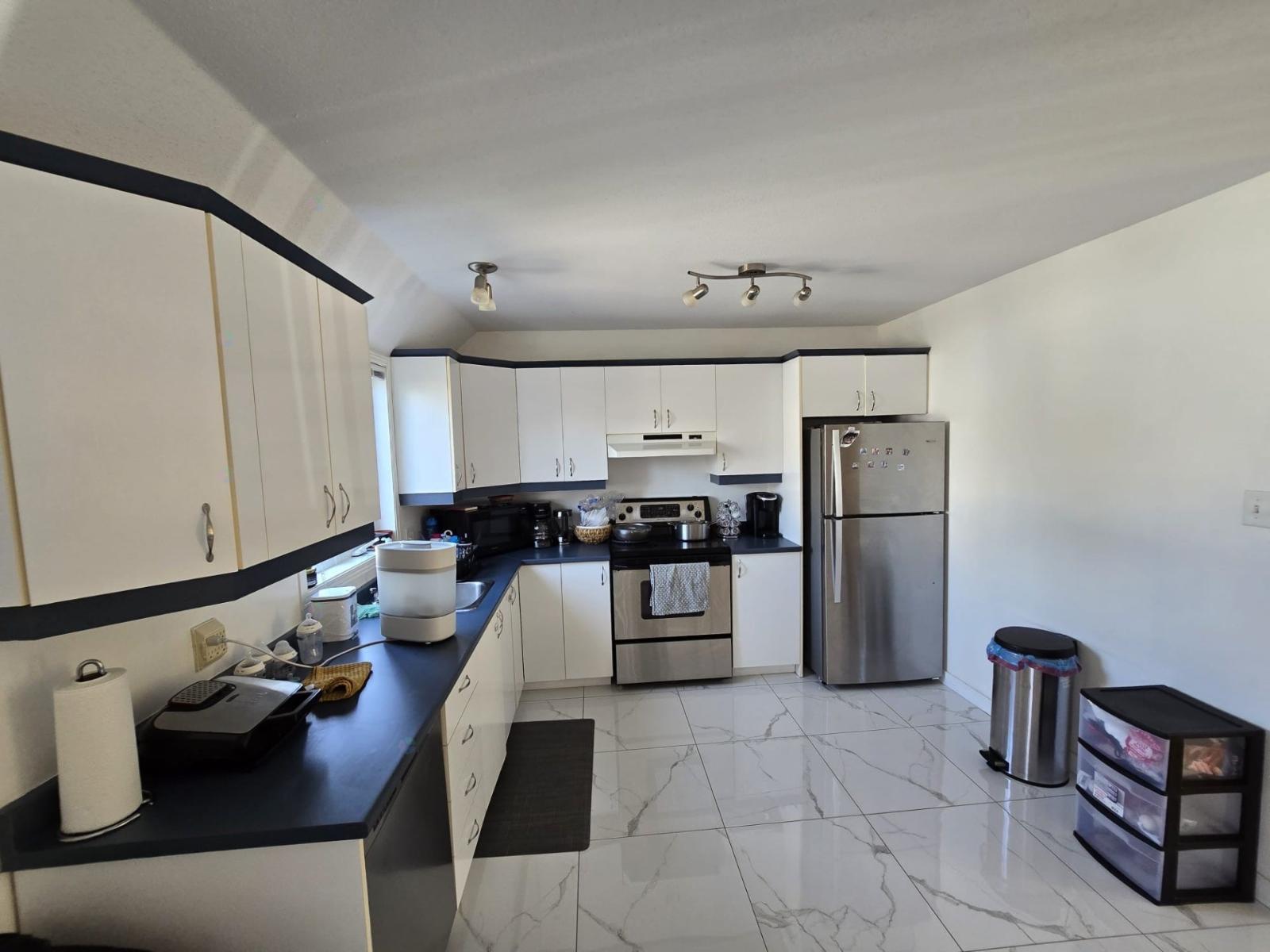 A kitchen with white cabinets and a black counter top.