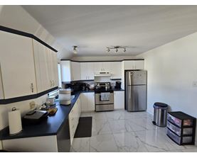A kitchen with white cabinets and a black counter top.