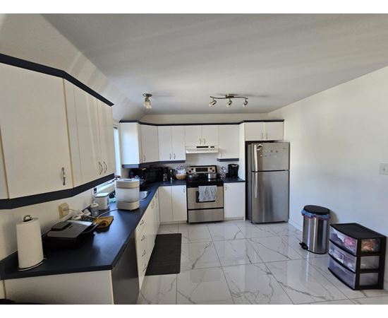 A kitchen with white cabinets and a black counter top.