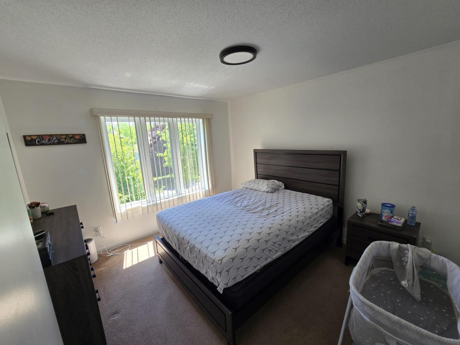 A bedroom with a bed, nightstand, and window.