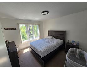A bedroom with a bed, nightstand, and window.