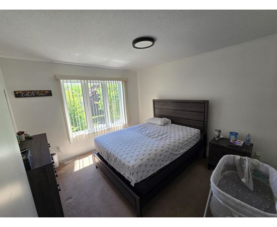 A bedroom with a bed, nightstand, and window.