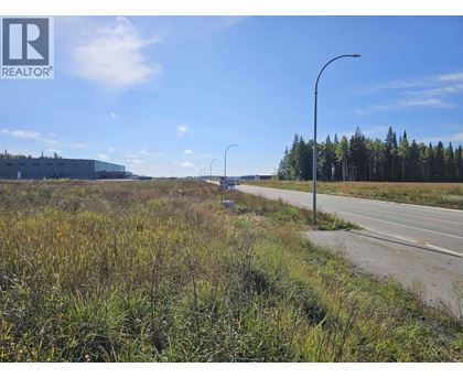 A road with a grassy area on the side and a building in the distance.