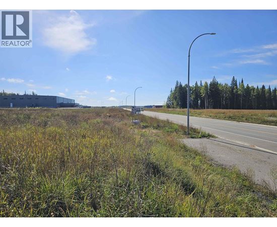 A road with a grassy area on the side and a building in the distance.