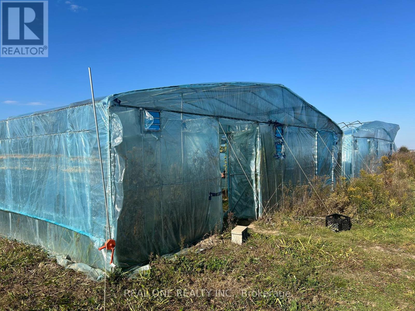 A large greenhouse with a blue tarp covering it.