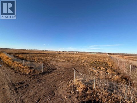 A dirt road stretches into the distance with a fence on the left side.