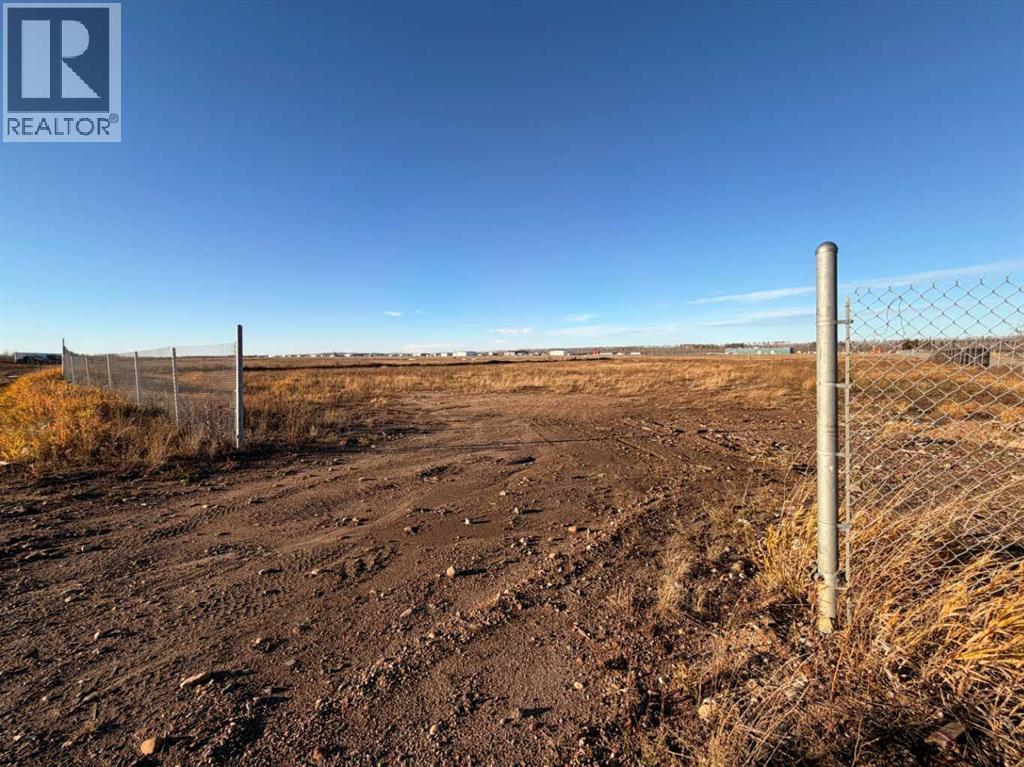 A barren landscape with a fence and a sign that says REALTOR.