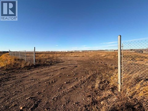 A barren landscape with a fence and a sign that says REALTOR.
