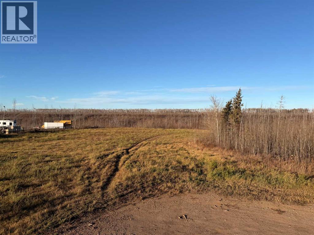 A dirt road leads to a white house in a field.