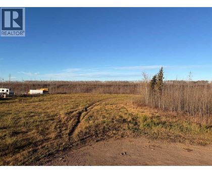 A dirt road leads to a white house in a field.