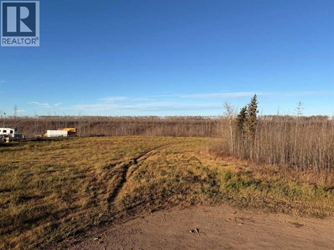 A dirt road leads to a white house in a field.