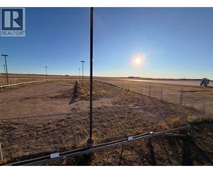 A sunny day at a construction site with a fence and a pole in the foreground.