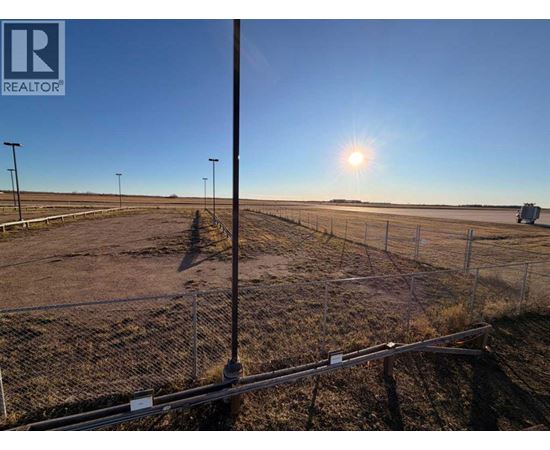 A sunny day at a construction site with a fence and a pole in the foreground.