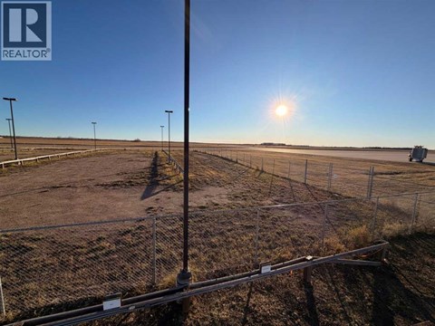 A sunny day at a construction site with a fence and a pole in the foreground.