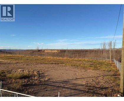 A field with a fence and a REALTOR sign in the corner.