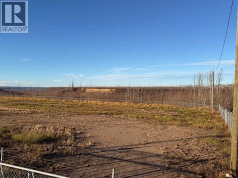 A field with a fence and a REALTOR sign in the corner.