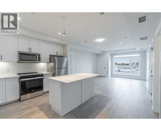 A modern kitchen with white cabinets and stainless steel appliances.
