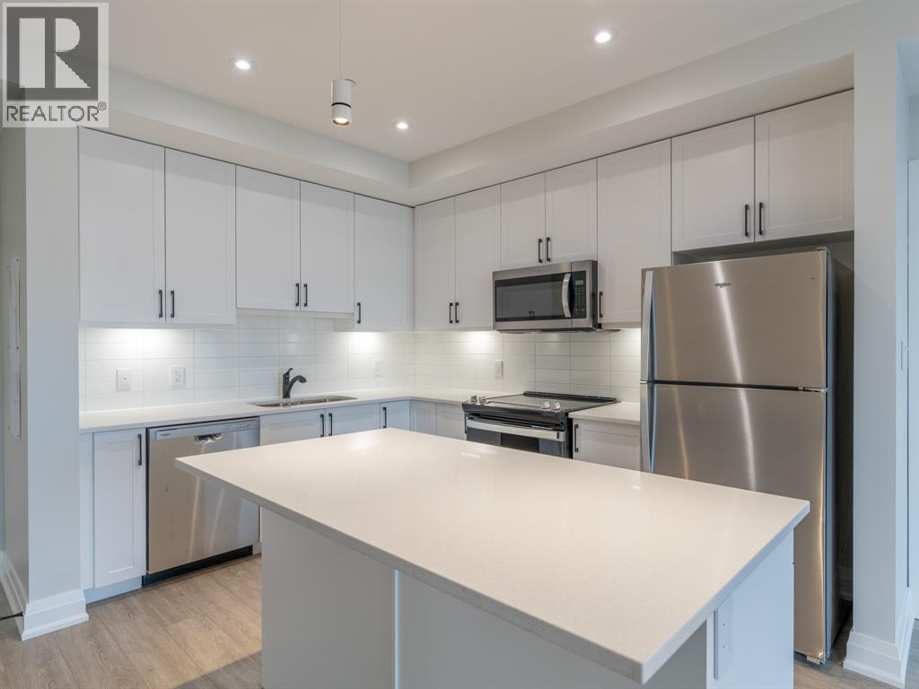 A modern kitchen with white cabinets and stainless steel appliances.