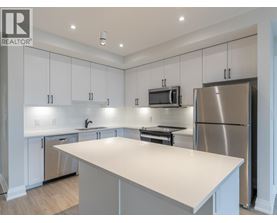 A modern kitchen with white cabinets and stainless steel appliances.