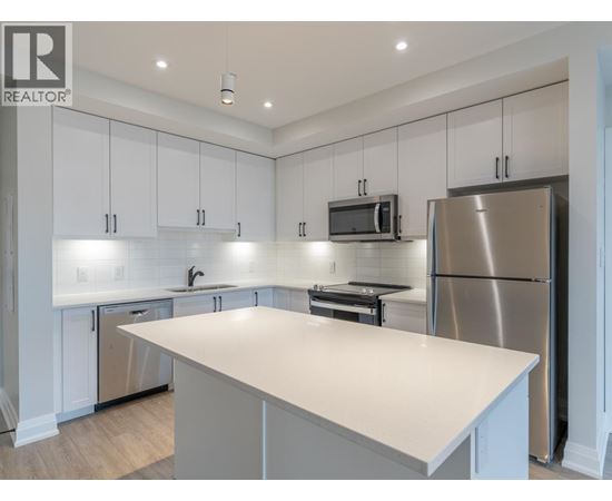 A modern kitchen with white cabinets and stainless steel appliances.