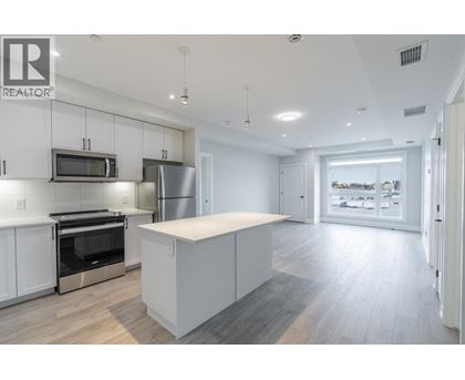 A modern kitchen with white cabinets and stainless steel appliances.