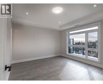 A spacious room with a large window and wooden flooring.