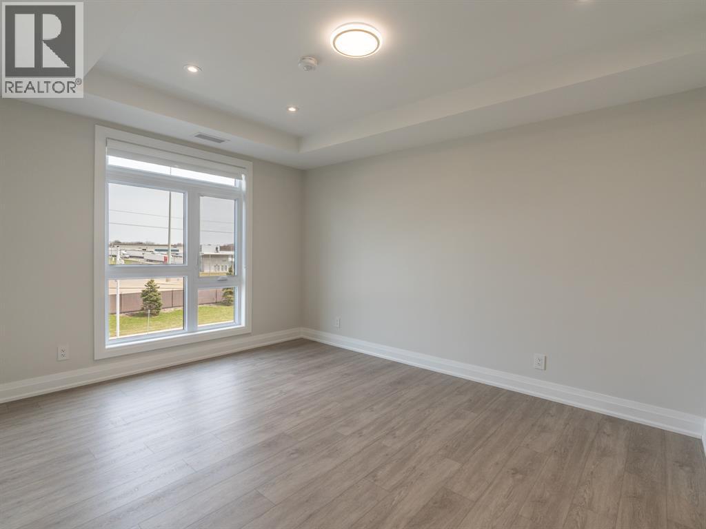 A spacious room with a large window and wooden flooring.