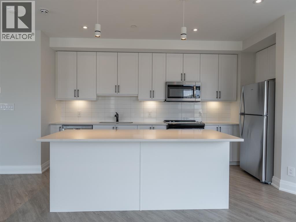 A modern kitchen with white cabinets and stainless steel appliances.
