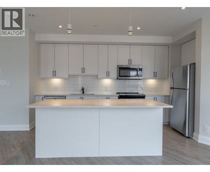A modern kitchen with white cabinets and stainless steel appliances.