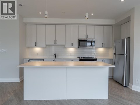 A modern kitchen with white cabinets and stainless steel appliances.