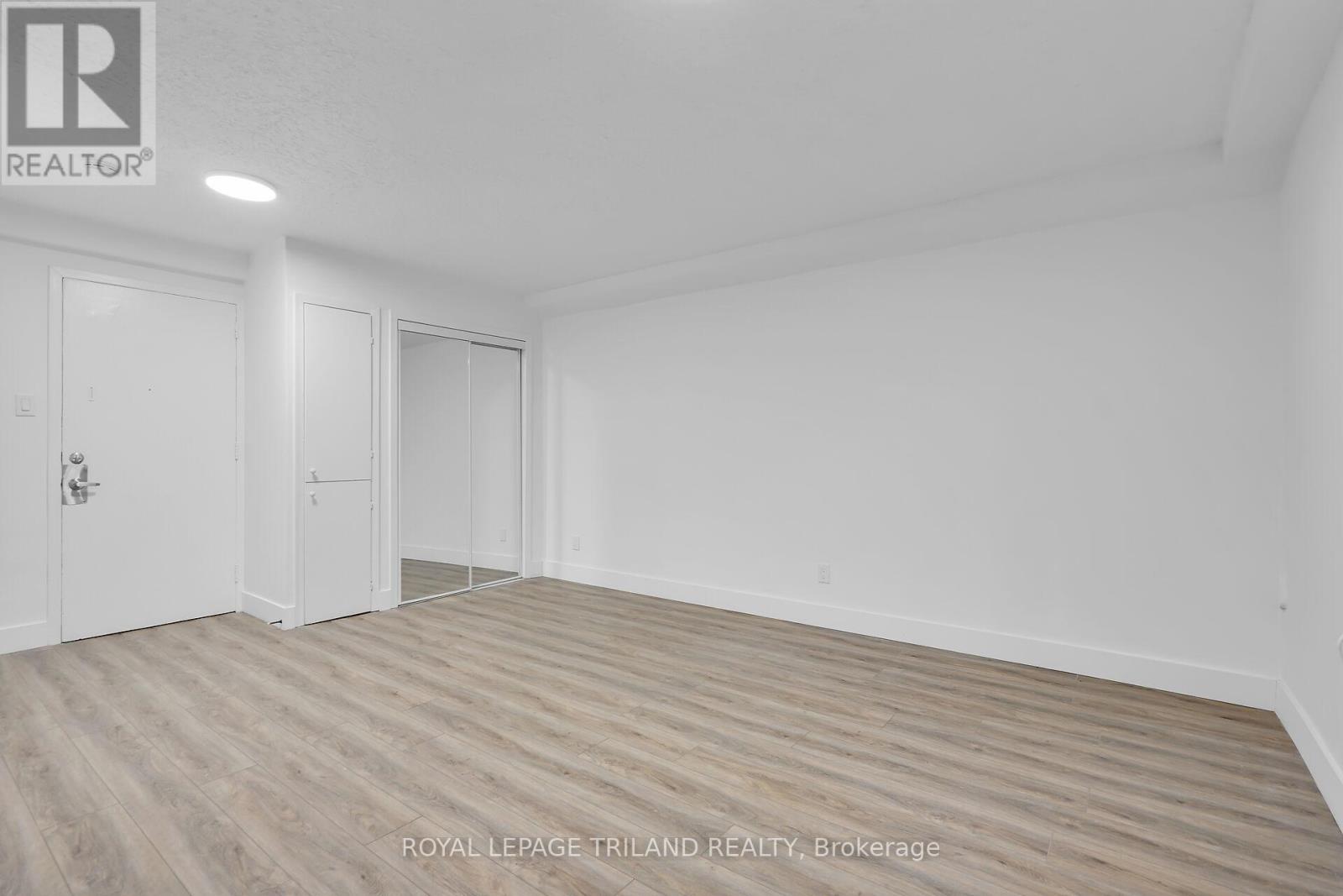 A white room with wooden flooring and two doors.