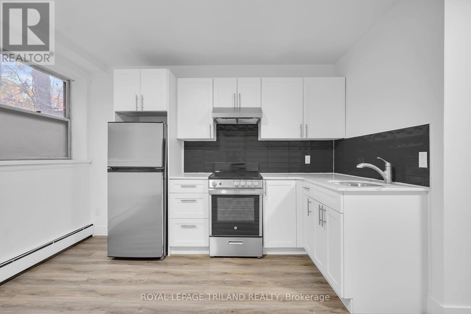A modern kitchen with white cabinets and stainless steel appliances.