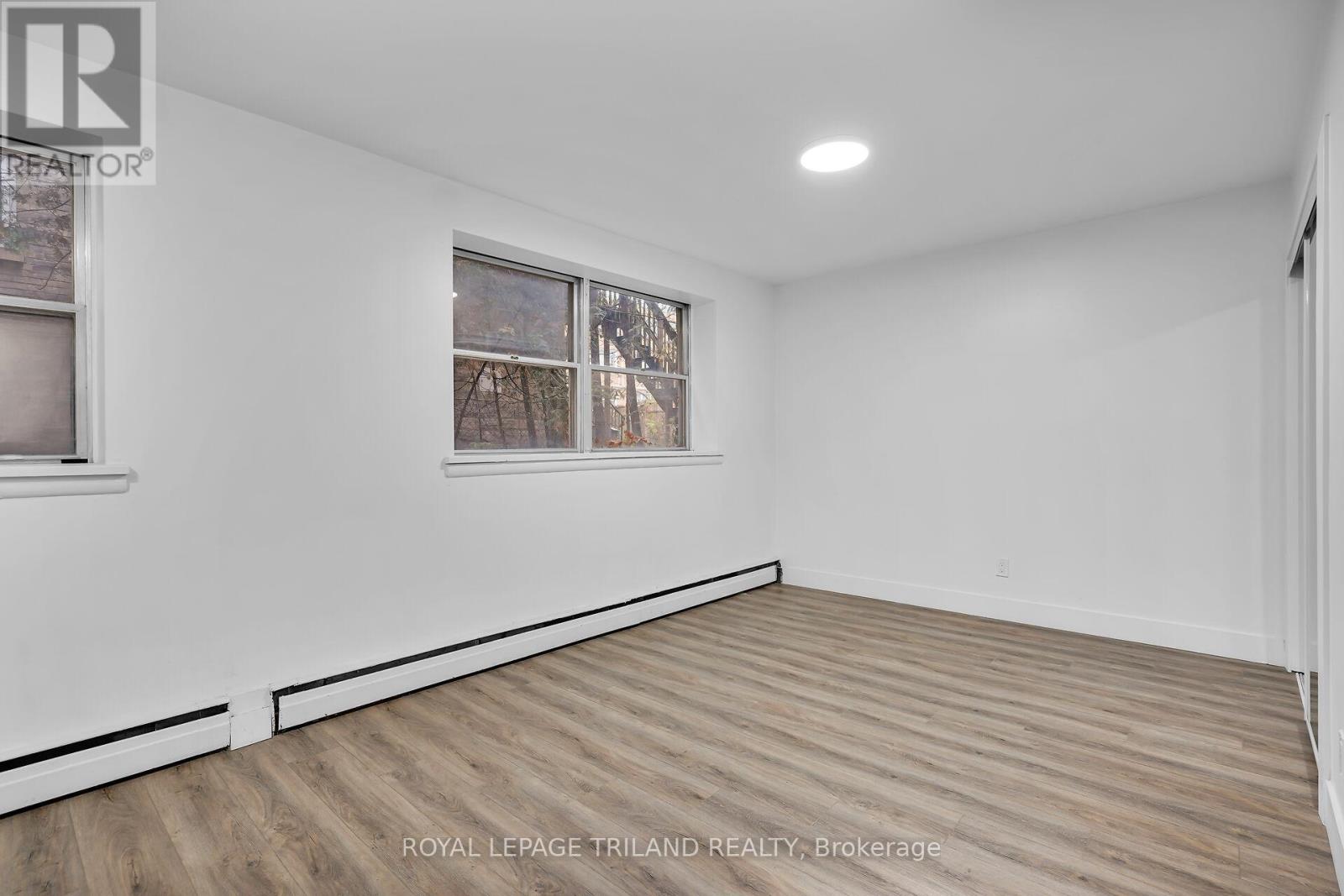A white room with a window and wooden flooring.